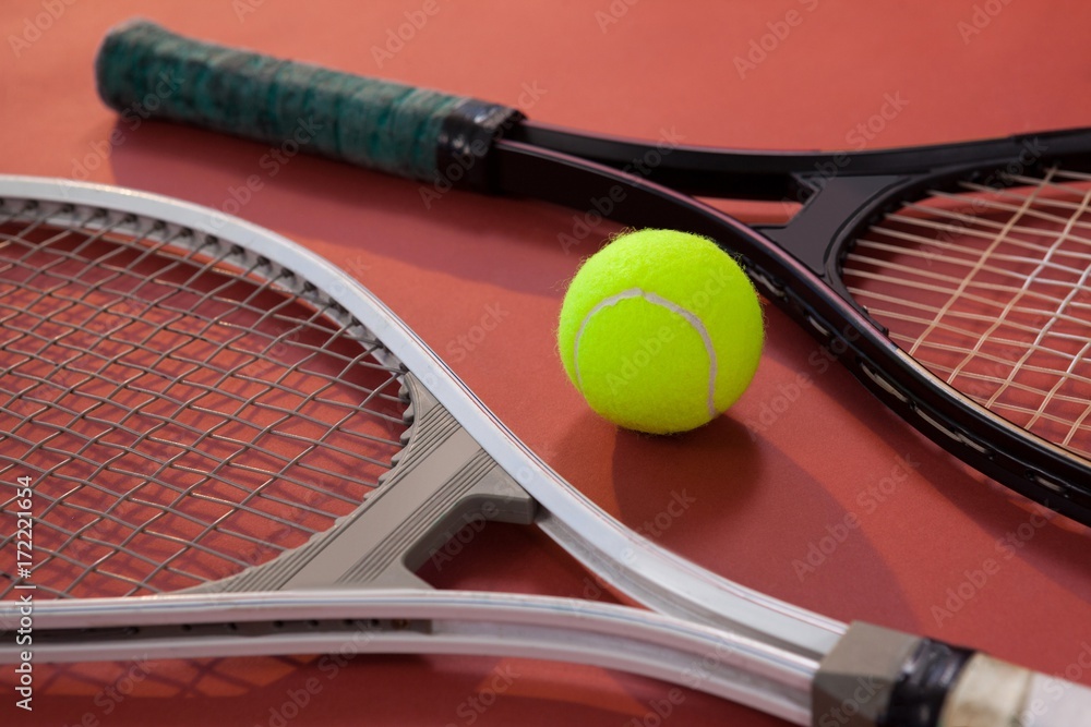 High angle view of fluorescent yellow ball amidst tennis rackets