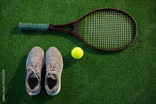 Overhead view of racket with tennis ball and sports shoes