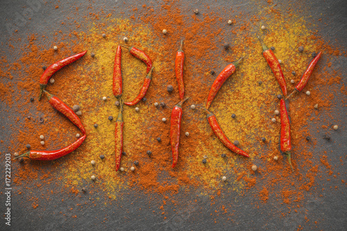 Spicy / Geschrieben mit Chilischoten in Paprika und Currypulver mit Pfeffer auf Schieferplatte