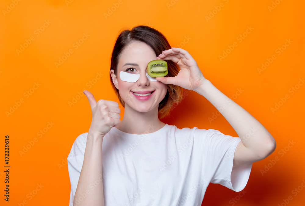 Woman using eye patch for her eyes and holding kiwi Woman using eye patch for her eyes and holding kiwi