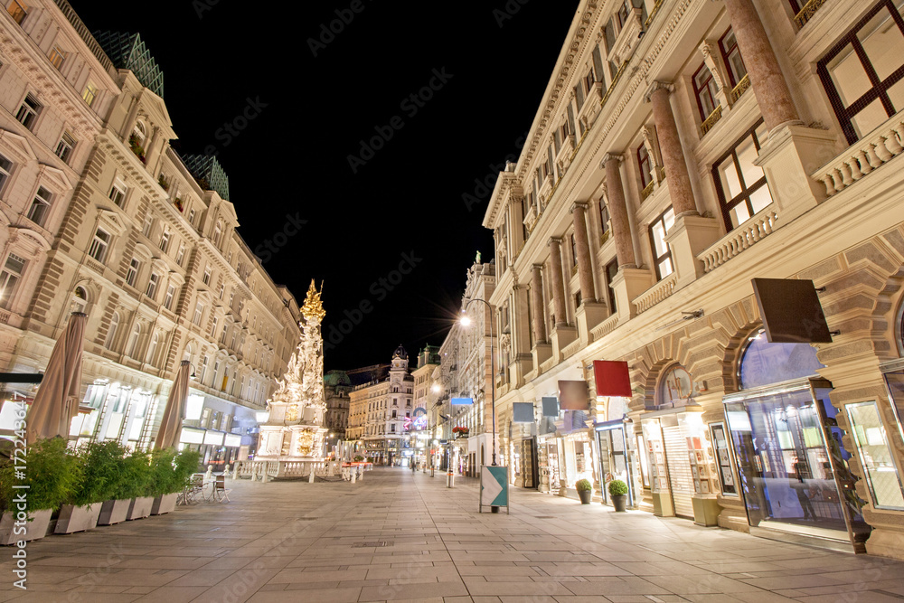 Pestsaule between illuminated buildings during night at Graben street in Vienna, Austria