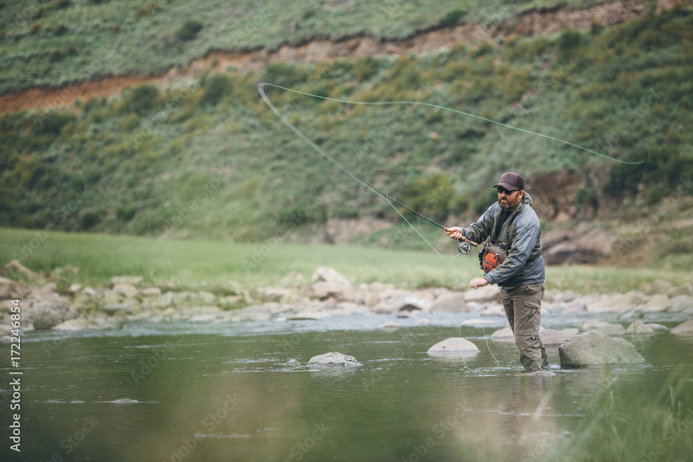 fly fisherman casting into a wilderness river fly fisherman casting into a wilderness river