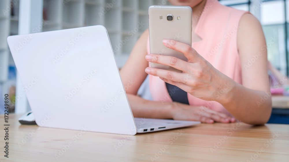 Fototapeta premium female hands using phones and working with a laptop in office at desk