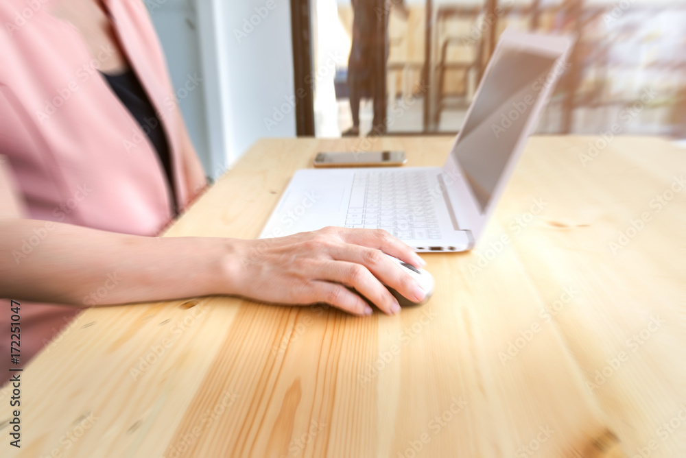 Blurred female hands working with a laptop in office at desk Blurred female hands working with a laptop in office at desk