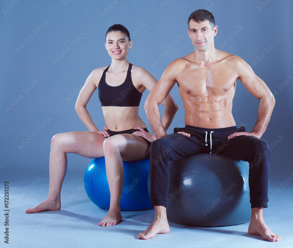 Obraz premium Two smiling people with fitness ball in the gym. Personal fitness instructor. Personal training. Gym workout.