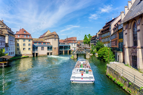 Traditional colorful houses in La Petite, with tourists taking a boat ride along traditional colorful houses on idyllic river Lauch in summer, Colmar, Alsace, France