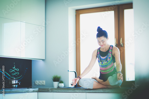 Young beautiful woman sitting at the kitchen table in the lotus position. Woman. Yoga