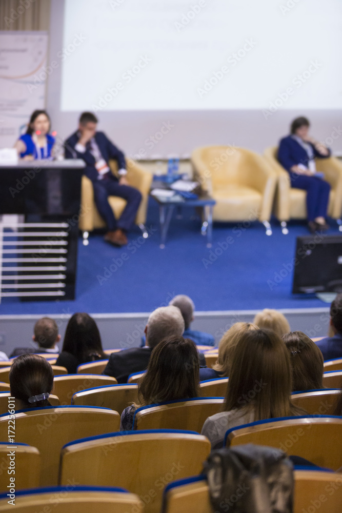 Obraz premium Female Host Speaking at Stage In Front of The Audience During Business Conference in Congress Hall. Concepts of Business and Entrepreneurship.