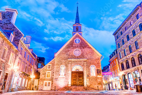 Lower old town street in Quebec City, Canada on la place Royale at dusk, night or twilight with Notre-dame-des-victories church and people with evening lights photo