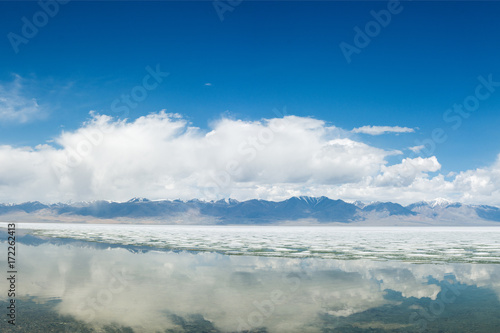 panoramic view of fluffy white clouds reflecting in mirror water of lake   © photollurg