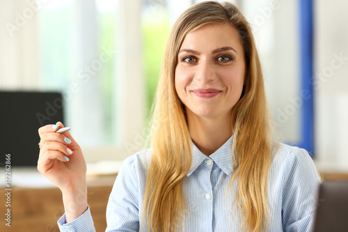 Beautiful smiling girl at workplace hold silver pen