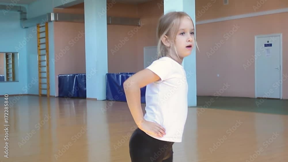 A beautiful girl is engaged in dancing in the dance hall. The child looks at the reflection and performs the exercises. Dancing school. A beautiful girl is engaged in dancing in the dance hall. The child looks at the reflection and performs the exercises. Dancing school.