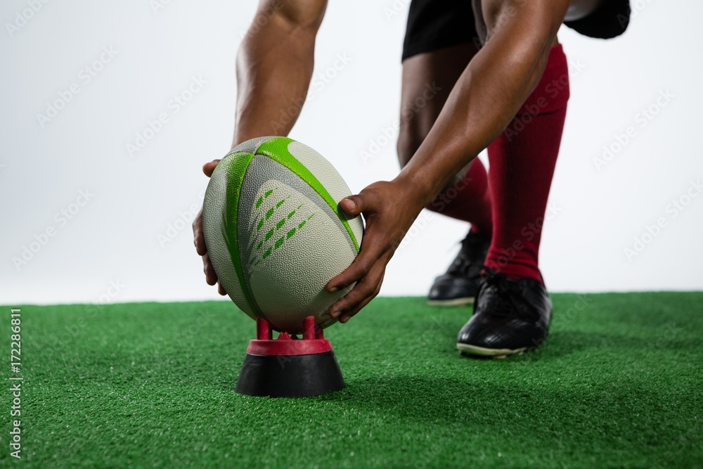 Fototapeta premium Low section of sportsman keeping rugby ball on tee