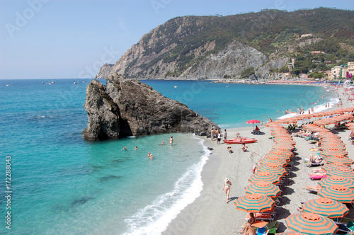 rows of orange  stripped beach umbrellas on a private beach Monterosso al Mare,  Cinque Terre, Italy
