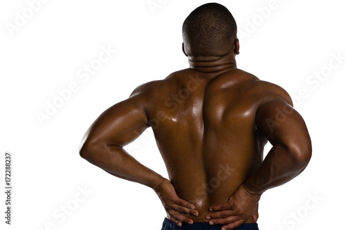 Rear view of shirtless sportsman suffering from back pain