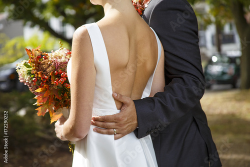 groom and bride with autumn bouquet outdoors. closeup of a married couple. Goose bumps and shivers at the bride. the bride in a wedding dress with a deep neckline at the back photo