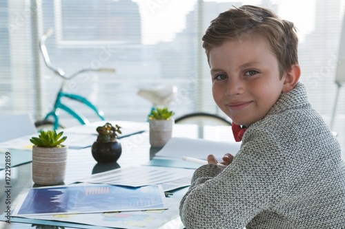 Boy as business executive smiling while sitting in office photo