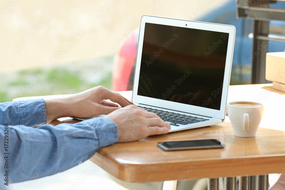 Fototapeta premium Young man working with laptop at table