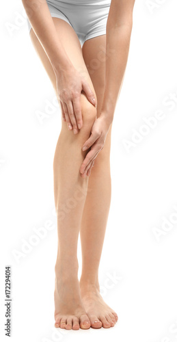 Young woman suffering from leg pain on white background © Africa Studio