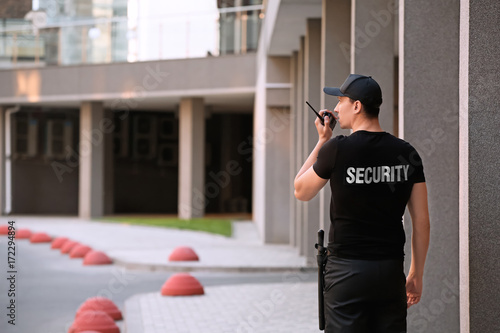 Fototapeta Male security guard with portable radio, outdoors