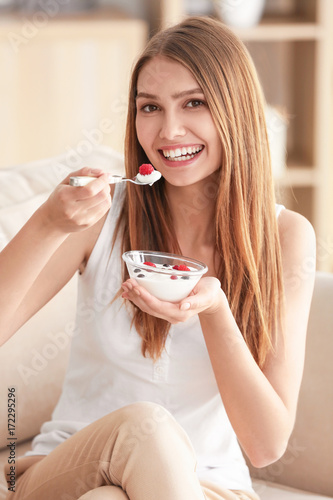 Young woman eating yogurt o...