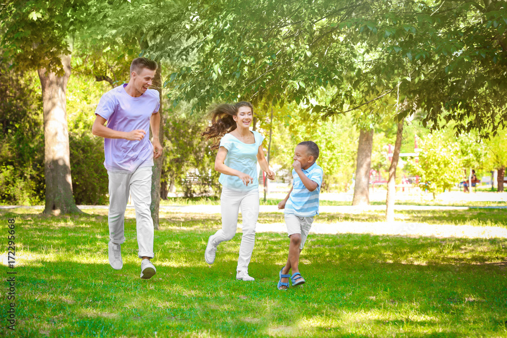 Young family with adopted African American boy having fun outdoors