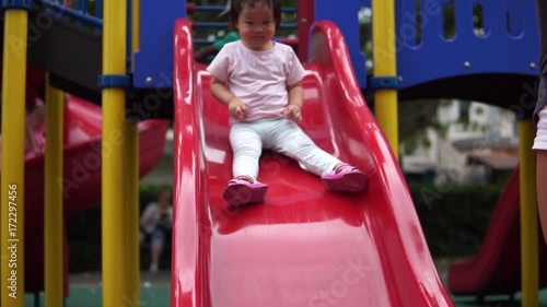 Asian Chinese Toddler sliding down play slide in slow motion