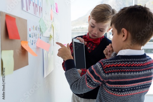 Kids as business executives discussing over whiteboard photo