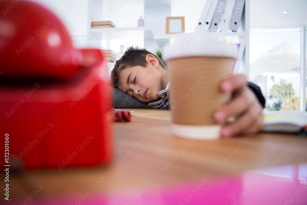 Boy as business executive sleeping while holding coffee cup Boy as business executive sleeping while holding coffee cup