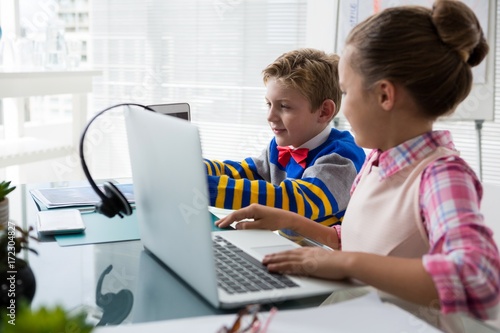 Kids as business executive interacting while using laptop photo