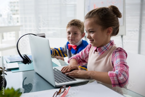 Kids as business executive interacting while using laptop photo