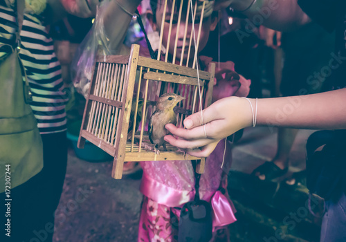 Asian girl with her mother to set free a little bird for merit from the cage.