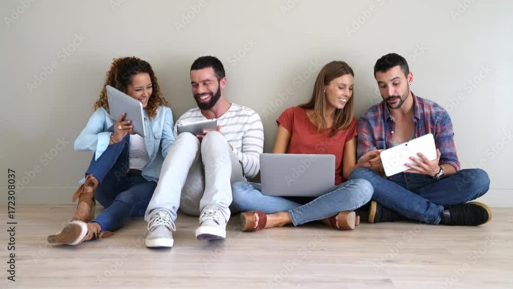 Group of friends using laptop and tablet, sitted on floor