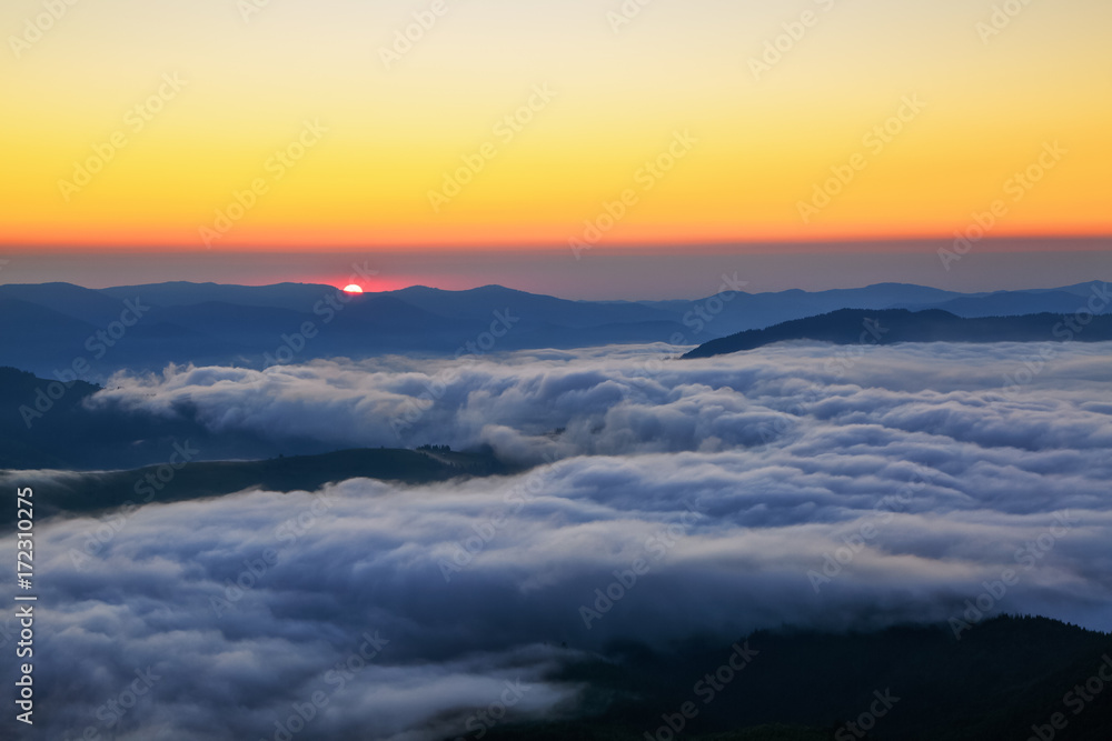 Scarlet sun at a dawn, which seems to swim out from the mountain peaks, coloring boundless sky in orange shades. Scarlet sun at a dawn, which seems to swim out from the mountain peaks, coloring boundless sky in orange shades.