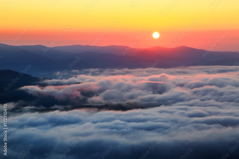Enchanting sunrise at the high mountains, and at the bottom there is textured thick fog.