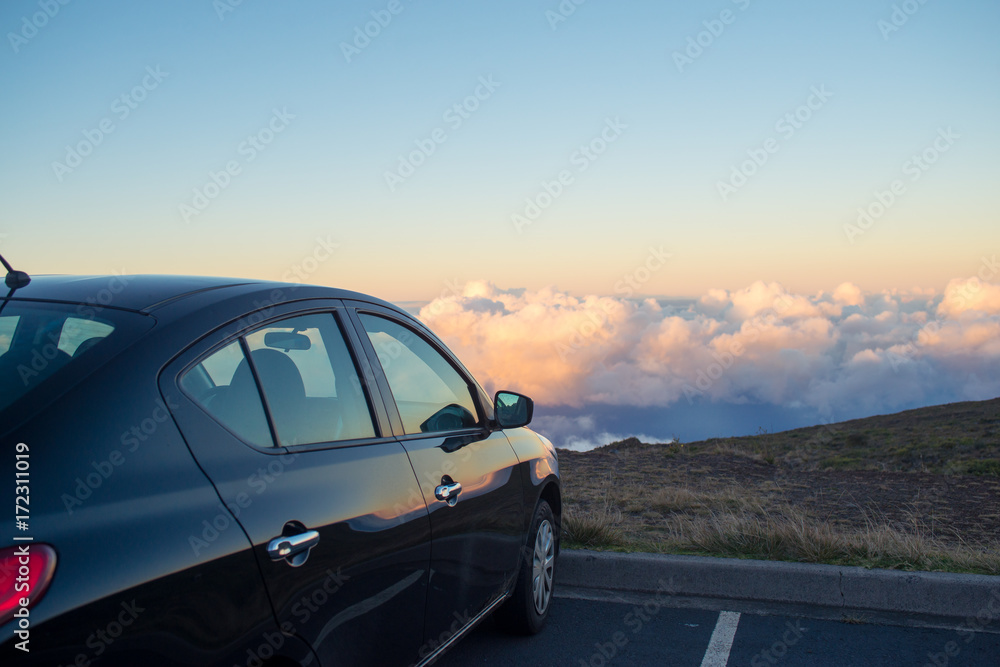 Black car in mountains above the clouds at sunset or sunrise