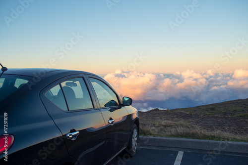 Black car in mountains above the clouds at sunset or sunrise