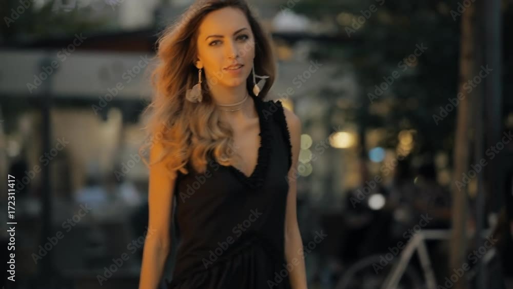 Pretty woman with beautiful hair walking in a evening city street, slowmotion Pretty woman with beautiful hair walking in a evening city street, slowmotion