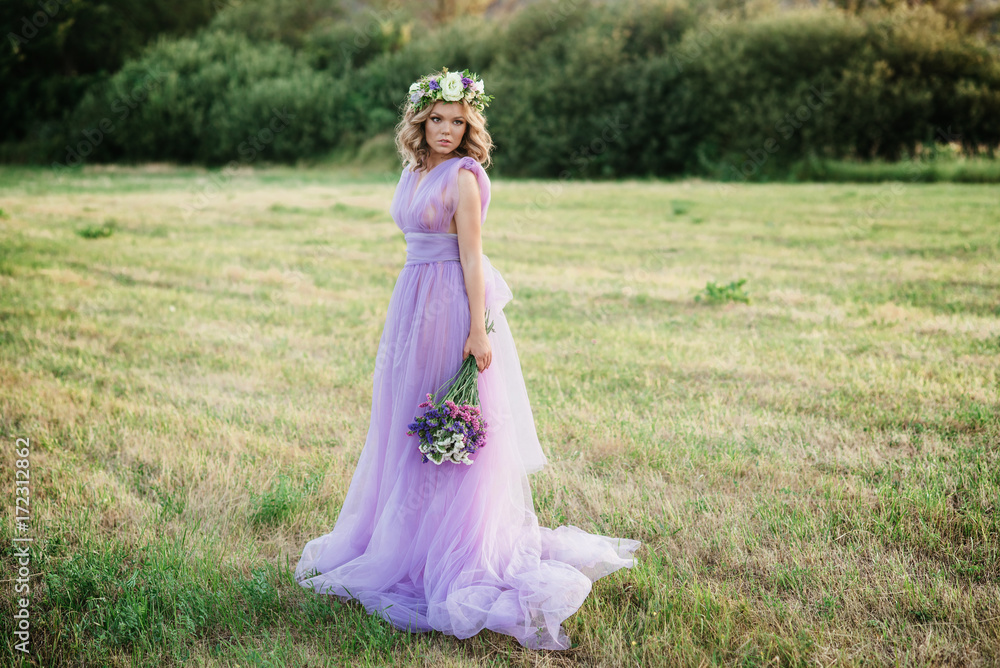 beauty woman portrait with wreath of flowers on head at sunset. bride in purple dress Outdoor. soft focus