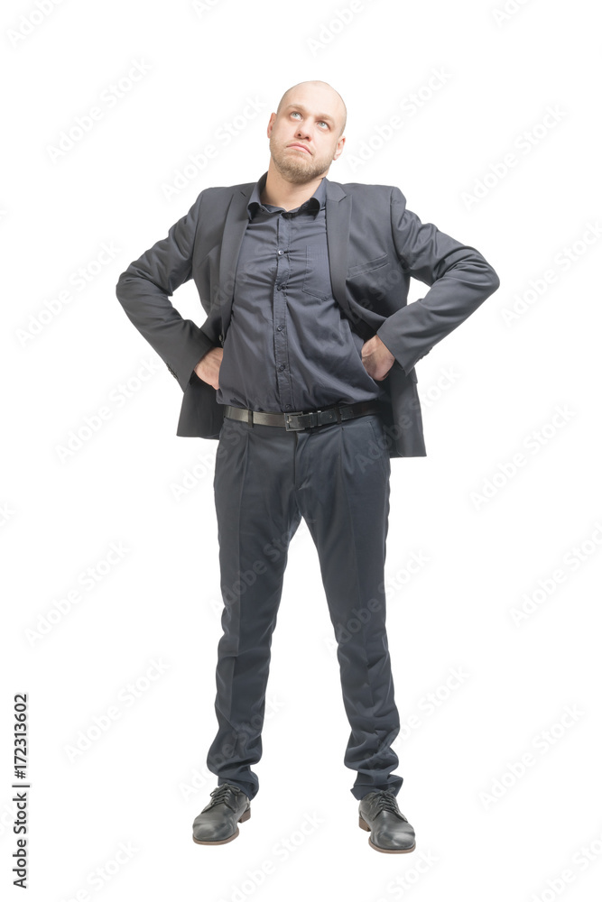 Unshaven bald man in a gray suit standing with hands on hips and looking up. Isolated Unshaven bald man in a gray suit standing with hands on hips and looking up. Isolated
