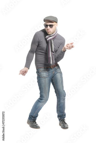 Unshaven bald man wearing a cap, jeans, sunglasses and a scarf dancing a strange dance. Isolated