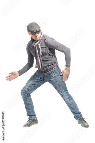 Unshaven bald man wearing a cap, jeans, sunglasses and a scarf dancing a strange dance. Isolated