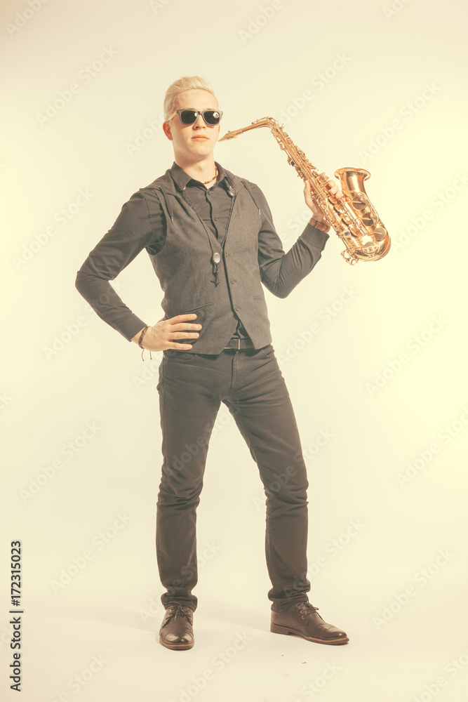 Naklejka premium Elegant blond man dressed in black holding a saxophone. Toned