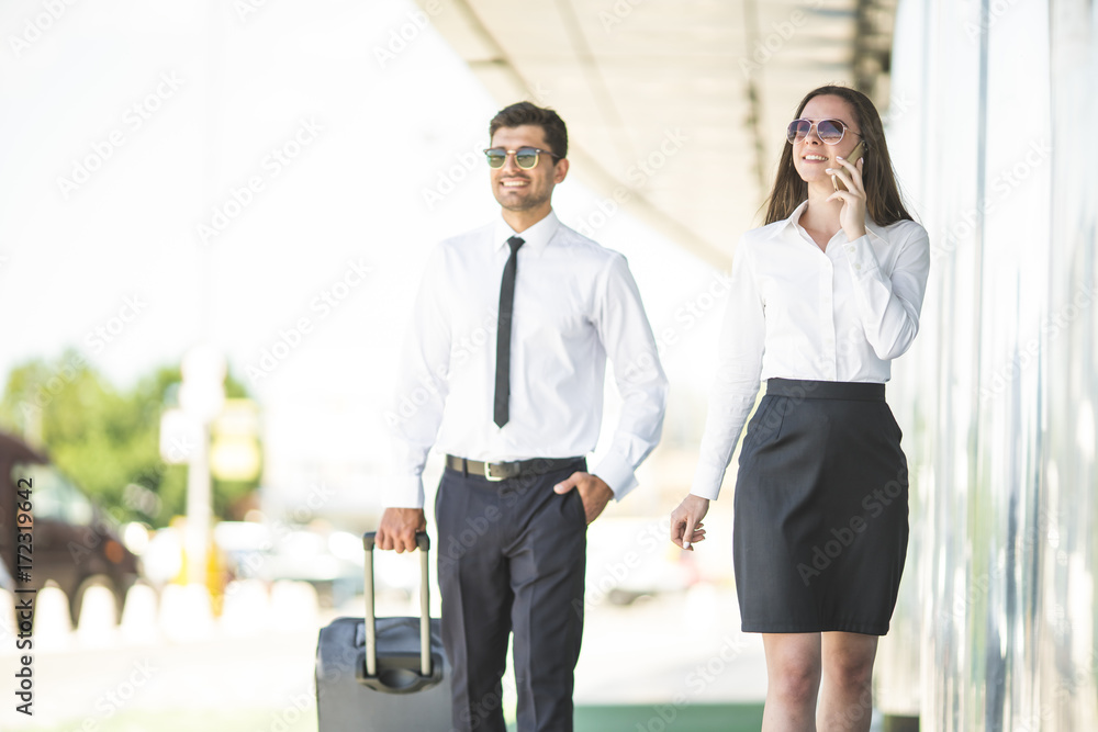 The happy business man and woman phone and walk with a suitcase The happy business man and woman phone and walk with a suitcase