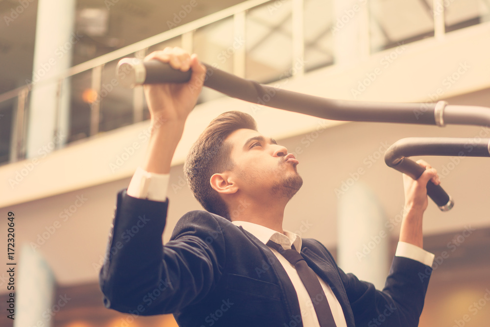 Handsome young man in a black suit, white shirt and tie training in the gym Handsome young man in a black suit, white shirt and tie training in the gym