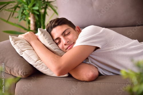 Foto Man napping on a couch clinging to cushions at home