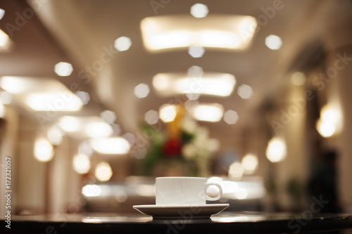 A white coffee or tea cup on the black wooden table with beautiful bokeh background at 5 stars hotel