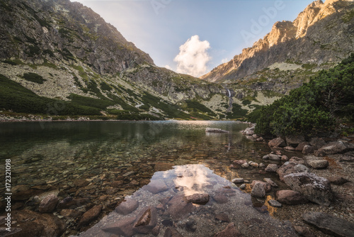 Mountain Lake with Waterfall and Rocks in Foreground at Sunset. Velicka Valley, High Tatra, Slovakia.