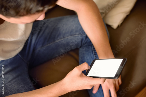 Young boy on a couch using a smartphone top view