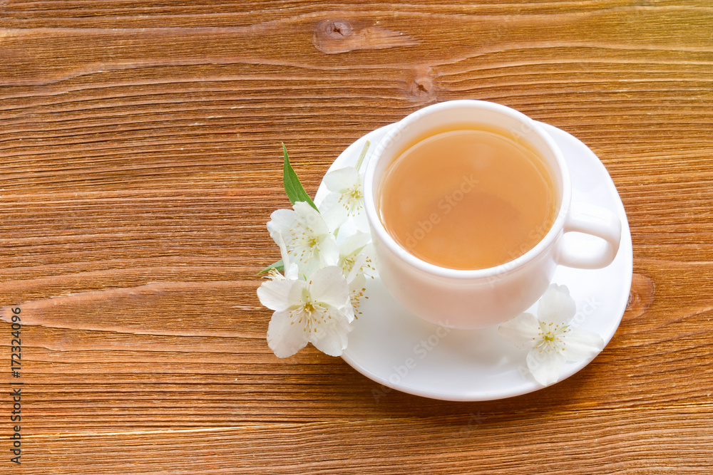 Obraz premium White mug of tea with jasmine on a wooden table. Top view